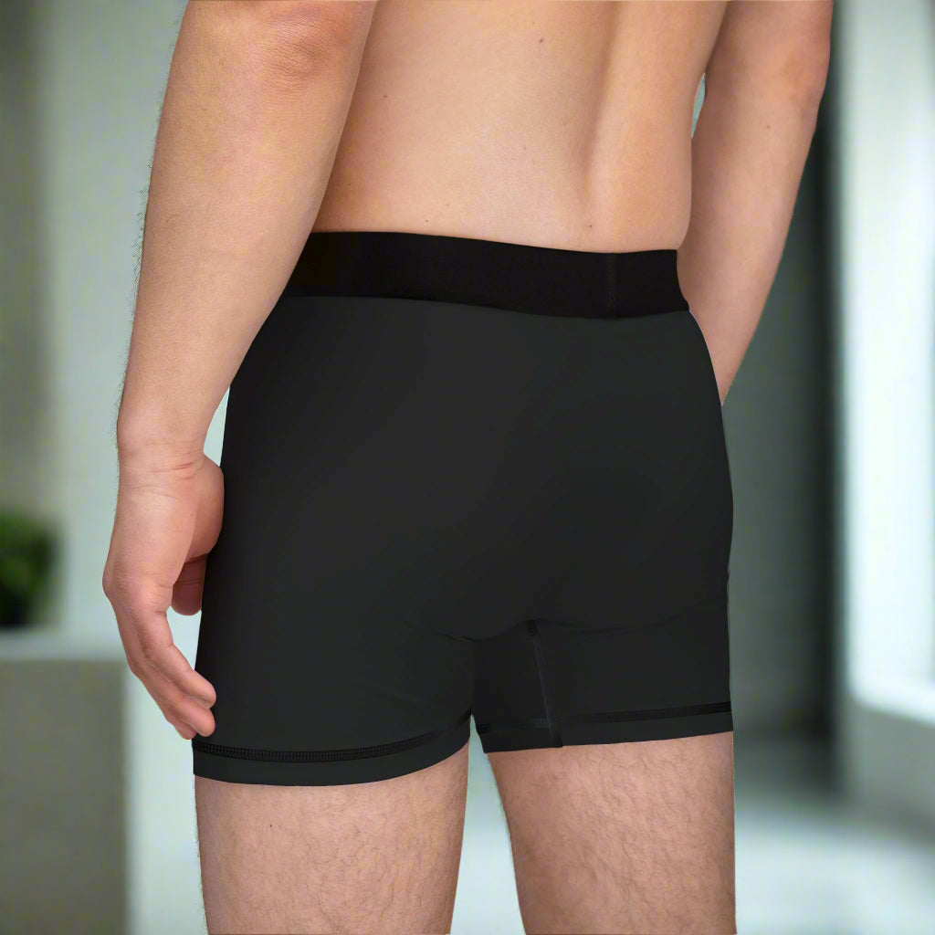 Black boxer briefs worn by a person on a white background